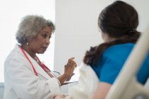 Médecin femme senior avec tablette numérique faisant des rondes, parler avec le patient dans le lit d'hôpital — Photo de stock