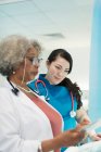 Жінка-лікар і медсестра з цифровим планшетом розмовляють в лікарні — стокове фото