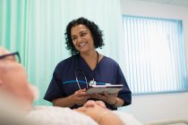 Krankenschwester mit digitalem Tablet macht Runde, spricht mit Patientin im Krankenhauszimmer — Stockfoto