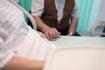 Liebevoller Senior hält Hand in Hand mit Frau im Krankenhausbett — Stockfoto