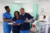 Ärzte und Krankenschwester mit medizinischen Diagrammen, die Runde machen, Beratung auf der Krankenhausstation — Stockfoto