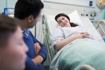 Посещение семьи улыбающийся пациент отдыхает на больничной койке — стоковое фото