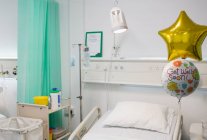Get Well balloons tied to bed in vacant hospital room — Stock Photo