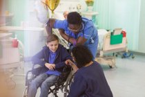 Врач и медсестра разговаривают с пациентом в инвалидном кресле в больничном отделении — стоковое фото