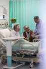 Médecin avec tablette numérique faisant des rondes, parler avec le couple aîné dans la chambre d'hôpital — Photo de stock