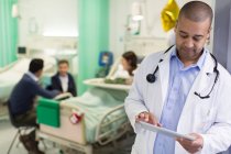 Médico masculino con tableta digital haciendo rondas en la sala de hospital - foto de stock
