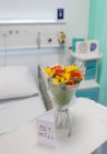 Blumenstrauß und Gute-Nacht-Karte auf Tablett im leeren Krankenhauszimmer — Stockfoto