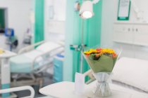 Flower bouquet and greeting card on tray in vacant hospital room — Stock Photo