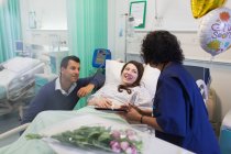 Médico com tablet digital fazendo rondas, conversando com casal na enfermaria do hospital — Fotografia de Stock