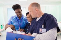 Лікарі і медсестра з медичною картою роблять раунди, консультування в лікарняній кімнаті — стокове фото