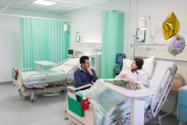 Homem visitando, conversando com esposa descansando na enfermaria do hospital — Fotografia de Stock