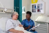 Krankenschwester im Gespräch mit Seniorin im Krankenhauszimmer — Stockfoto
