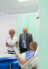 Médecins faisant des rondes, parlant avec le patient dans la chambre d'hôpital — Photo de stock