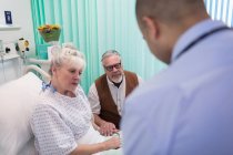 Doctor making rounds, talking with senior couple in hospital room — Stock Photo