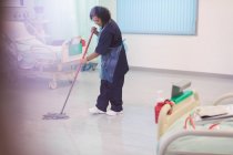 Mujer fregona ordenada piso de la sala del hospital - foto de stock