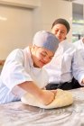 Young woman with Down Syndrome kneading dough in baking class — Stock Photo