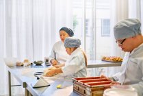Chef ajudando jovem estudante com Síndrome de Down na cozinha — Fotografia de Stock