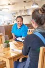Servidor femenino joven con síndrome de Down que sirve comida en la cafetería - foto de stock