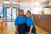 Retrato seguro de las mujeres jóvenes con síndrome de Down que trabajan en la cafetería - foto de stock