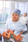 Portrait confiant jeune femme avec le syndrome de Down cuisson dans la cuisine — Photo de stock