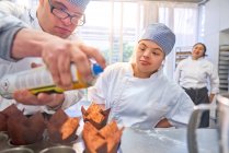 Junge Studenten mit Down-Syndrom backen Muffins in der Küche — Stockfoto