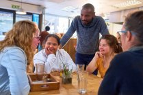 Mujeres jóvenes con síndrome de Down hablando con amigos en la cafetería - foto de stock