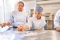 Young woman with Down Syndrome flouring surface in baking class — Stock Photo