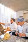 Шеф и студент с синдромом Дауна пекут хлеб на кухне — стоковое фото