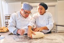 Chef teaching student with Down Syndrome how to form dough — Stock Photo