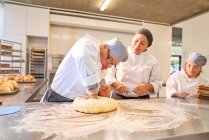 Chef guiding student with Down Syndrome kneading dough — Stock Photo