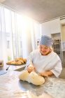 Smiling young woman with Down Syndrome kneading dough — Stock Photo