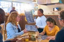 Молодий жіночий сервер Синдром Дауна дає меню клієнтам в кафе — стокове фото