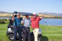 Portrait happy mature male golfers at golf cart on sunny course — Stock Photo