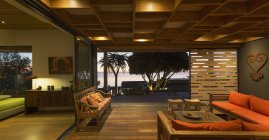 Illuminated modern, luxury home showcase interior living room open to patio — стоковое фото