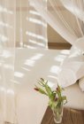 Tulpenstrauß in Vase auf Nachttisch neben Himmelbett mit Gaze-Vorhängen in ruhiger, moderner, luxuriöser Wohnung Vitrine im Inneren Schlafzimmer — Stockfoto