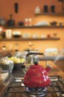 Chaleira de chá vermelho vapor em fogão na cozinha doméstica — Fotografia de Stock