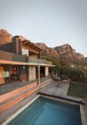 Montanhas atrás de moderno, casa de luxo vitrine casa exterior com piscina — Fotografia de Stock