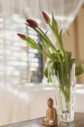 Tulip bouquet in vase and wooden Buddha statuette — Stock Photo
