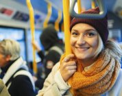 Retrato de la mujer joven segura de llevar gorra de siembra y bufanda en autobús. - foto de stock