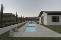 Розкішний басейн і будинок в сутінках — стокове фото