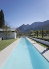 Lussuosa piscina soleggiata con montagne sullo sfondo — Foto stock