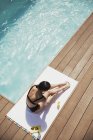 Mulher aplicando protetor solar para as pernas na piscina ensolarada de verão — Fotografia de Stock