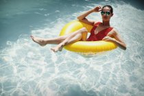 Retrato mulher confiante relaxante, flutuando no anel inflável na piscina ensolarada do verão — Fotografia de Stock