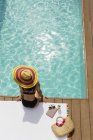 Woman in sun hat and bikini relaxing at sunny poolside — Stock Photo