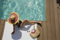 Mujer en sombrero de sol tomar el sol, relajarse en la soleada piscina de verano - foto de stock
