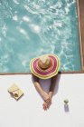 Woman in sun hat relaxing in swimming pool — Stock Photo