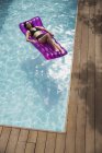 Ніжна жінка розслабляється на надувній плоті в басейні — стокове фото