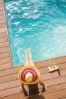 Donna in cappello da sole rilassante a bordo piscina estiva soleggiata — Foto stock