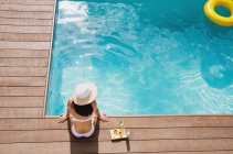 Mulher de chapéu de sol relaxante na ensolarada piscina de verão — Fotografia de Stock
