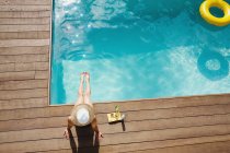 Жінка в сонячному капелюсі розслабляється, купається в сонячному літньому басейні — стокове фото